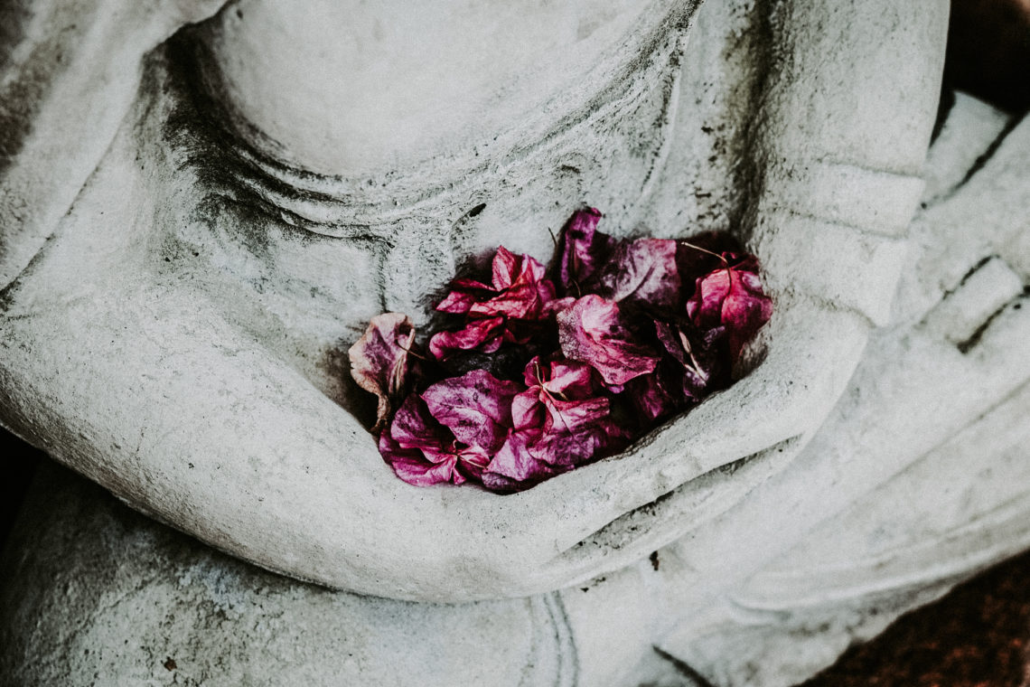 Buddha sitzend mit Blumen im Schoß