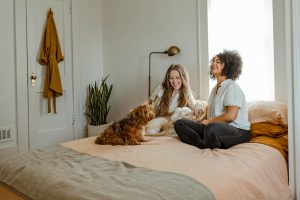 Zwei Freundinnen auf einem Bett mit Hund
