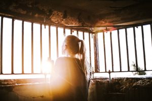 Frau schaut aus Gefängniszelle ins Licht